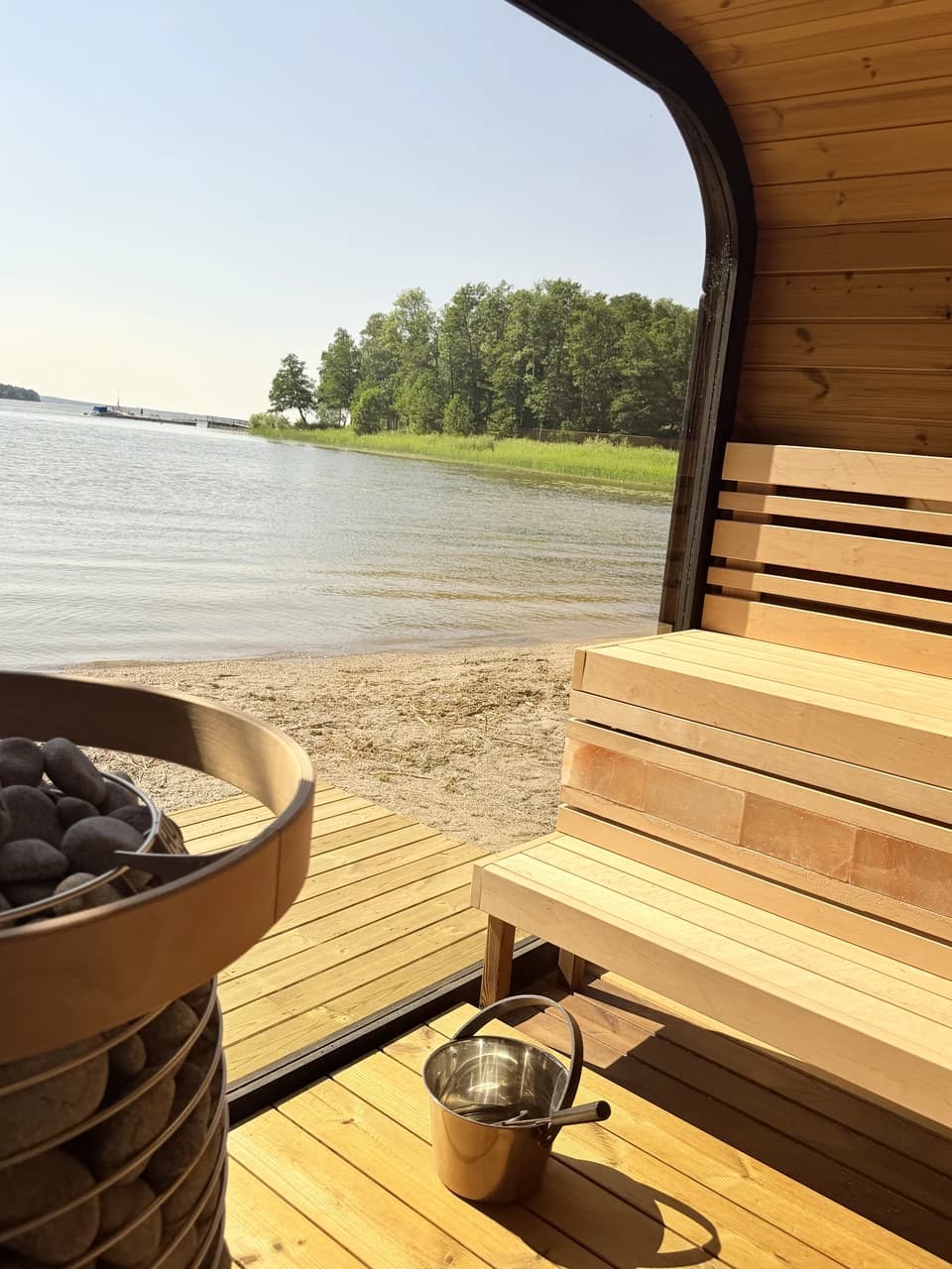 Insidan av bastun på Kaggeholm en solig sommardag, med aggregat, lavar och utsikt över Mälaren och sandstranden