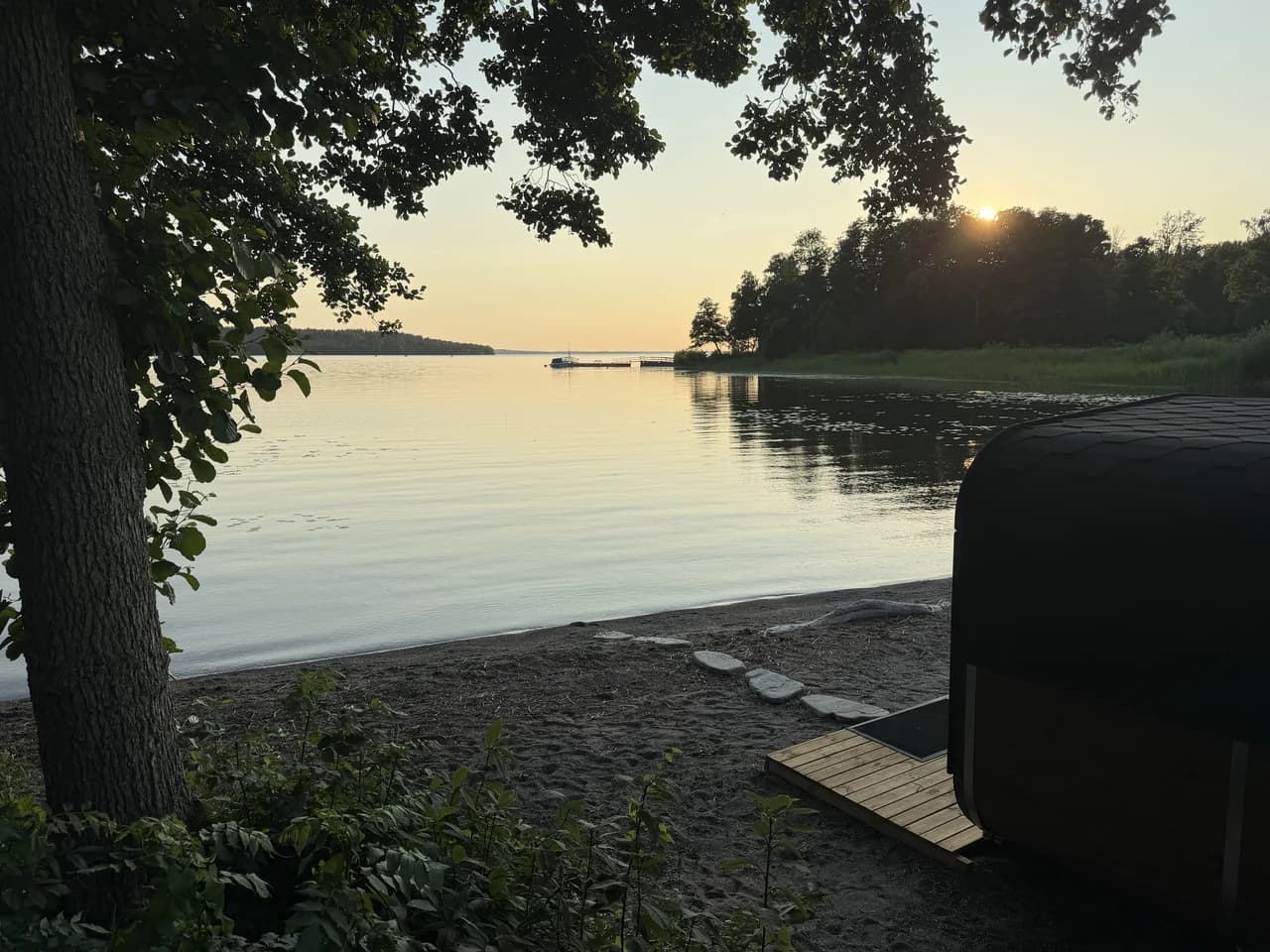 Solnedgång över Mälaren vid stranden på Kaggeholm, med bastun och trädäcket vid vattnet