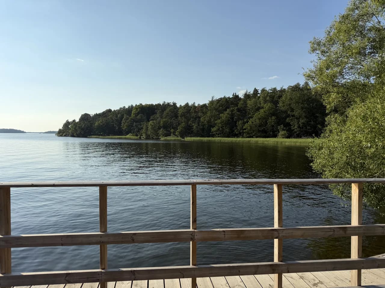 Badbryggan vid Riddersvik med räcke ut mot Mälaren och den skogklädda udden på andra sidan viken
