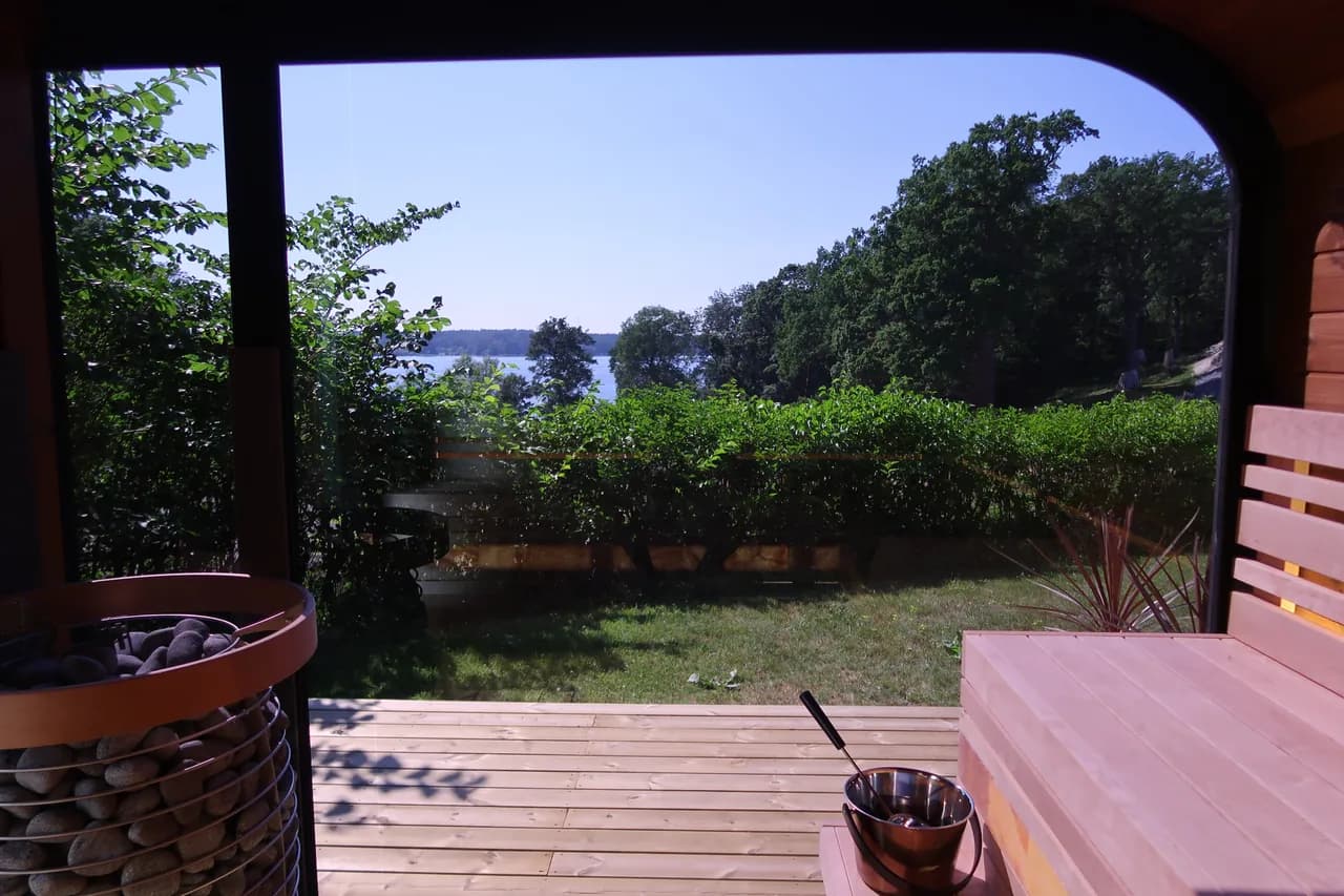 Utsikt från bastun vid Riddersvik ut mot trädäcket, häcken och Mälaren en solig sommardag
