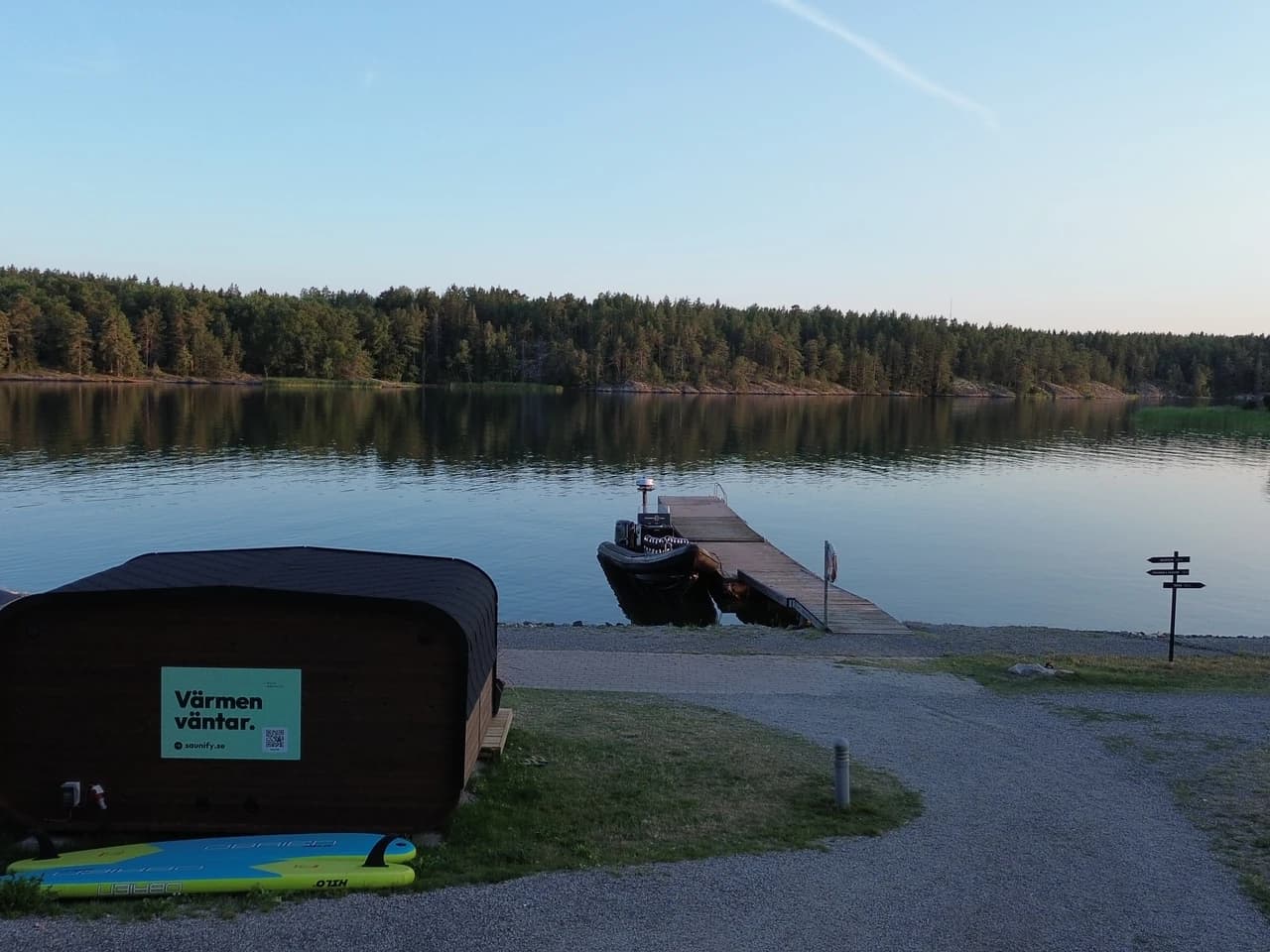 Bastun vid Skåvsjöholm från ovan, med bryggan, båten och skärgårdsviken omgiven av skog